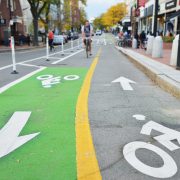 A bike lane separated by flex posts with a cyclist riding on it.